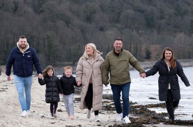A smiling family walk along a Scottish beach